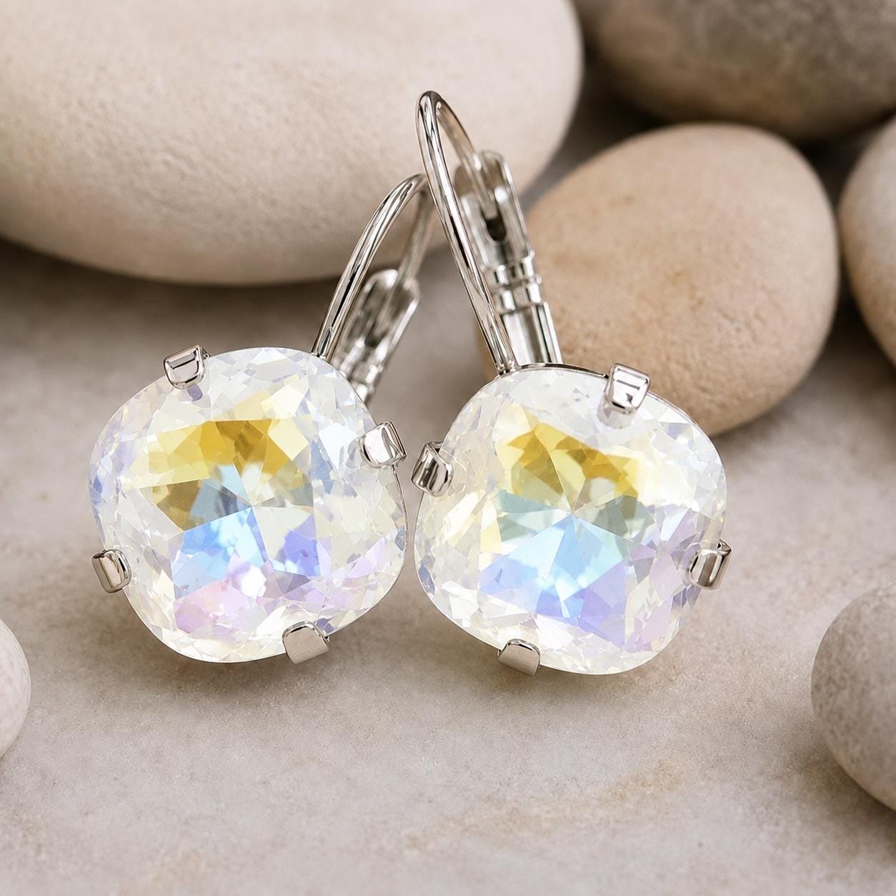 Sparkling Crystal cushion earrings displayed on a neutral stone background.