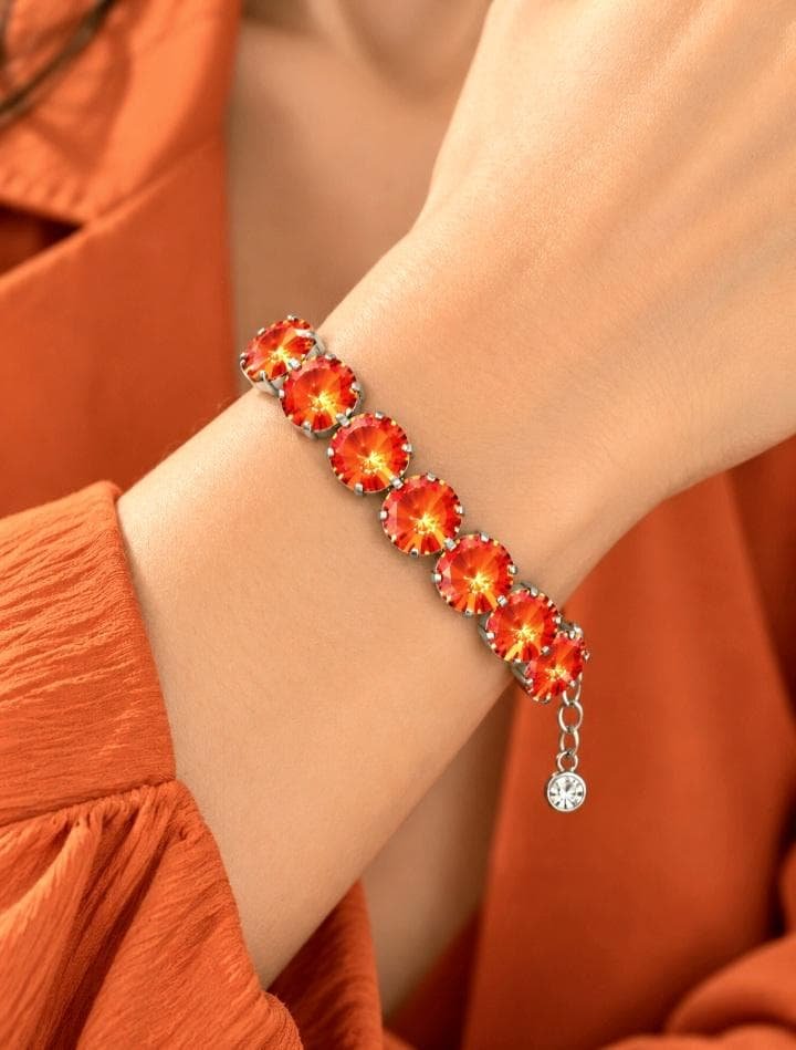 Woman wearing a bold orange crystal tennis  bracelet with large round Swarovski Rivoli stones on her wrist.