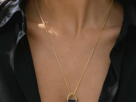 Fashion-inspired mini purse pendant necklace shown on a woman's neck.